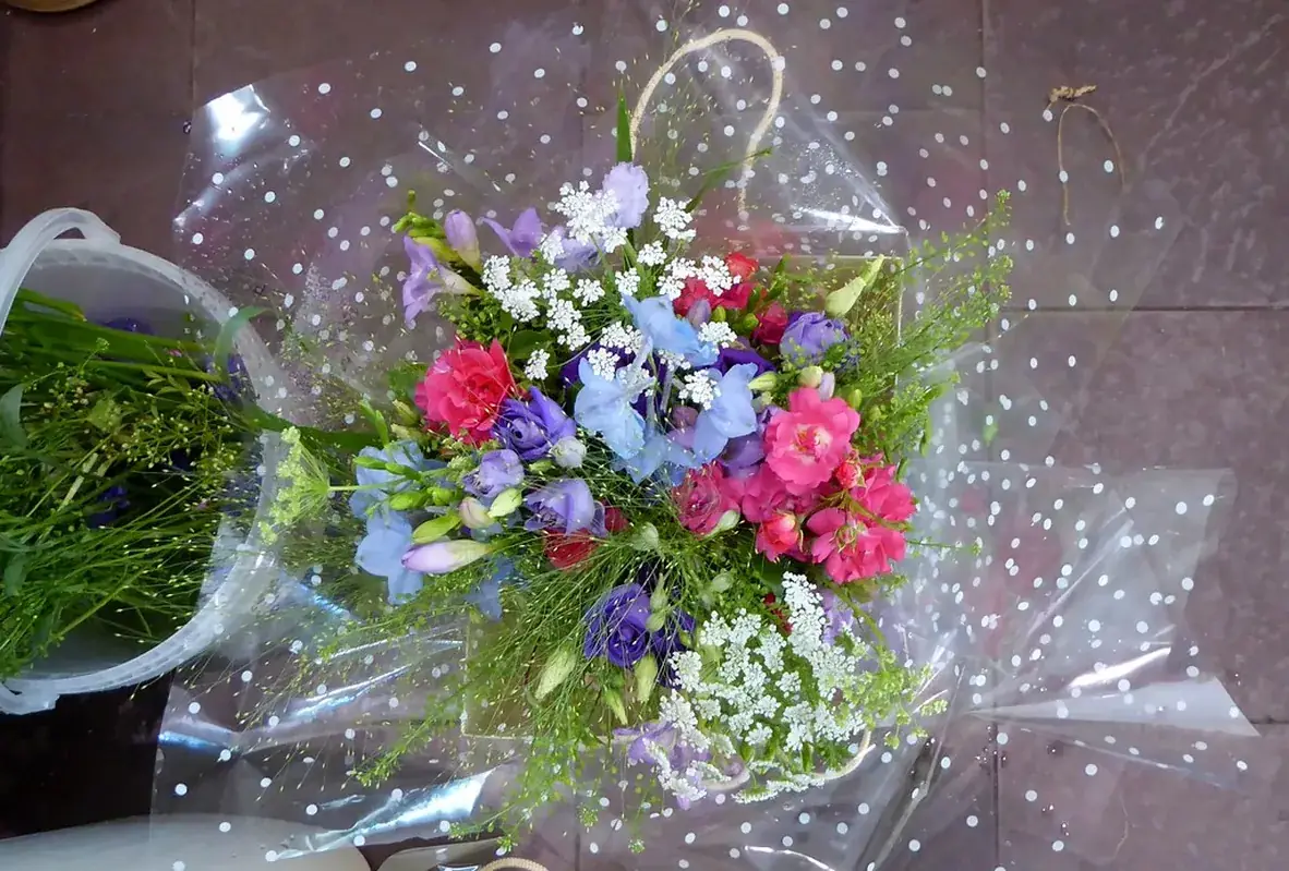A finished bouquet wrapped and resting on the workbench by the window