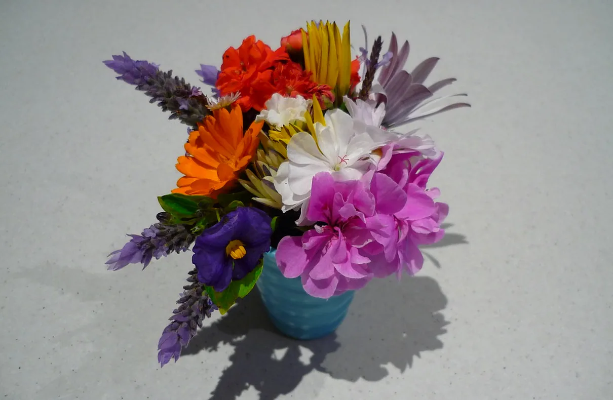 A small posy of mixed seasonal flowers in a glazed pot