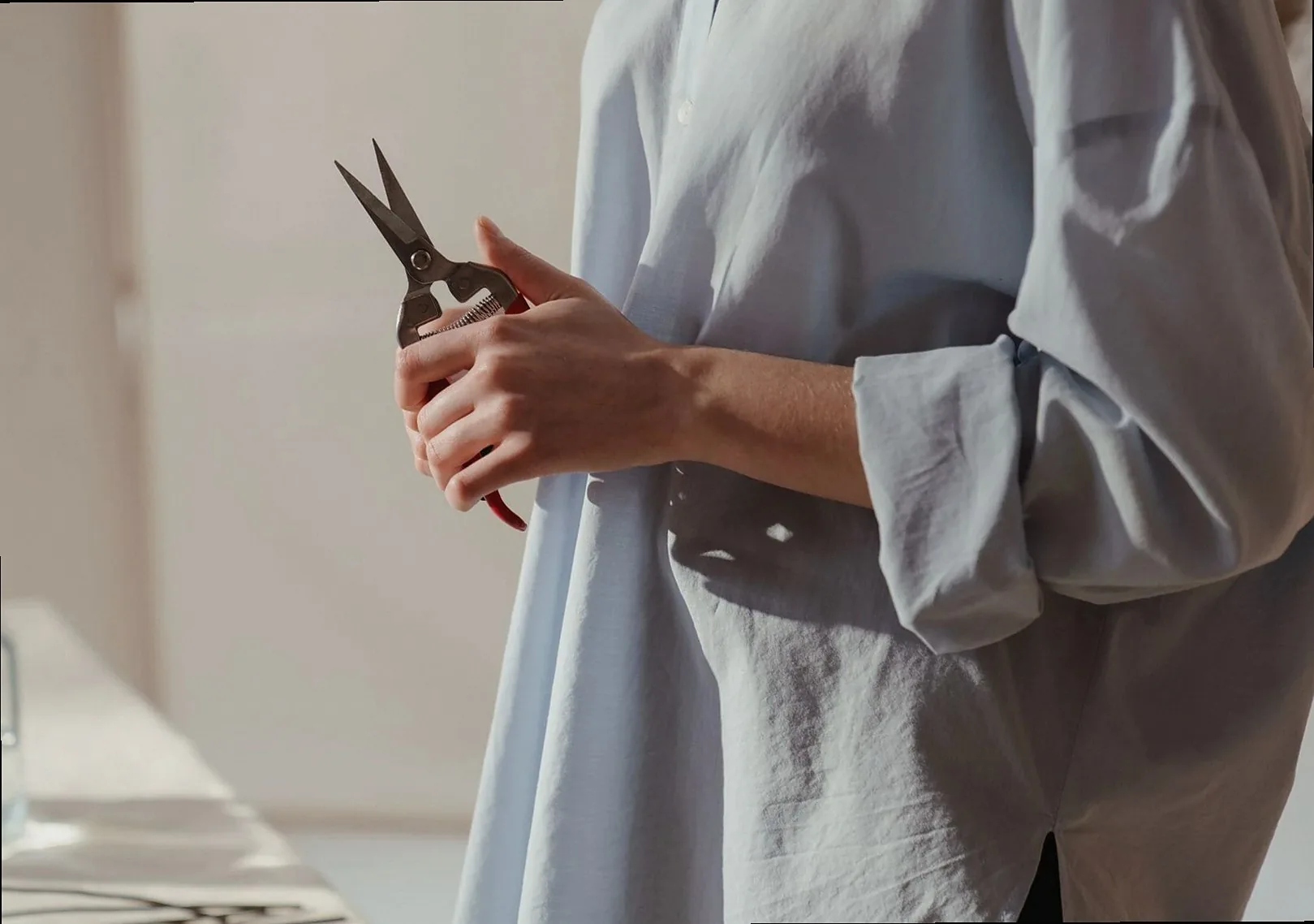 Hands in a blue shirt holding florist's scissors before trimming stems